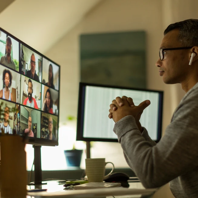 A man is sitting in front of his desktop and attending a conference call.