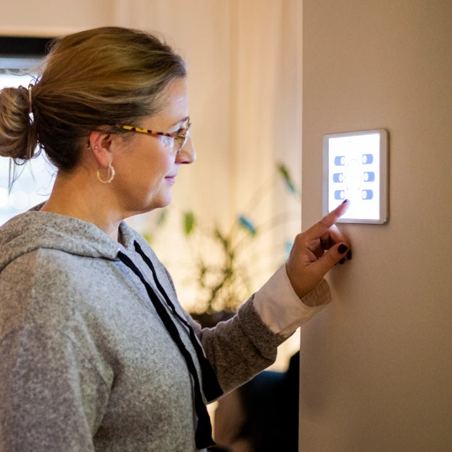 A woman is standing in front of the security system and checking it.