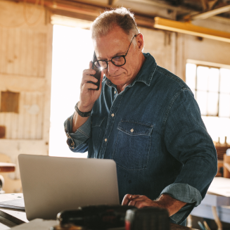 Small business owners taking a phone call, while working on his laptop