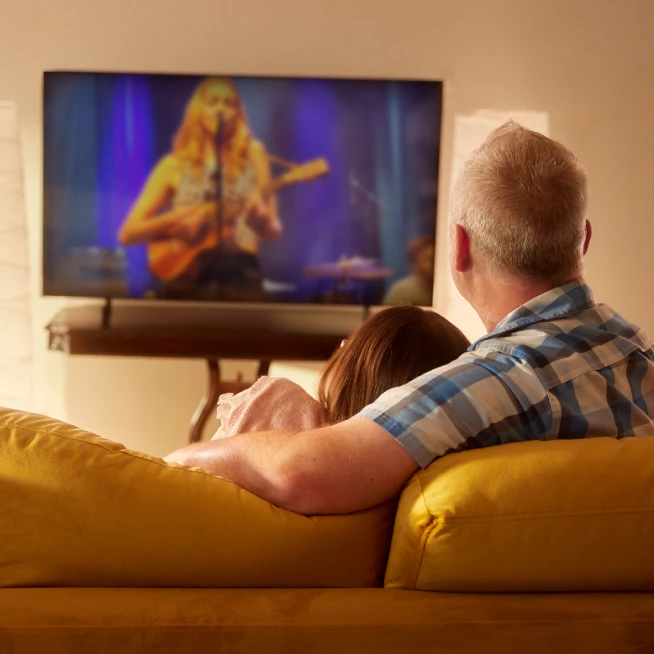 A girl and her dad sit on the couch and watching the favorite show on TV powered by Brightspeed internet.