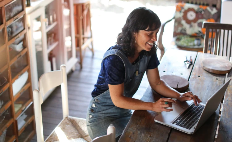 A young lady typing on a laptop powered by Brightspeed home internet.