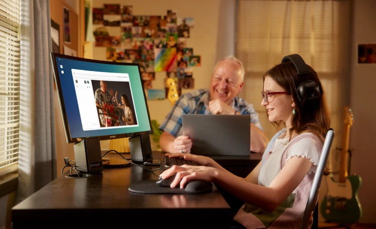 A woman wearing headphones looking at a picture of herself on the computer.