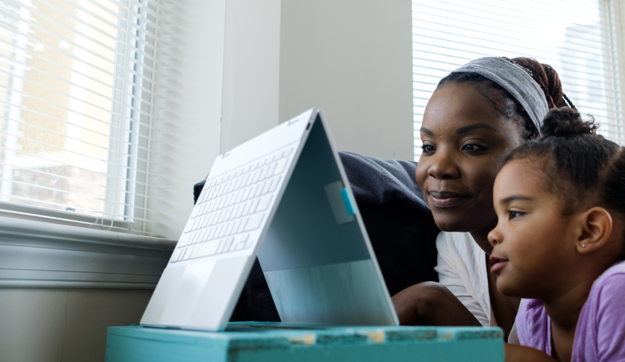 Two sisters watching a video on a backwards folding laptop